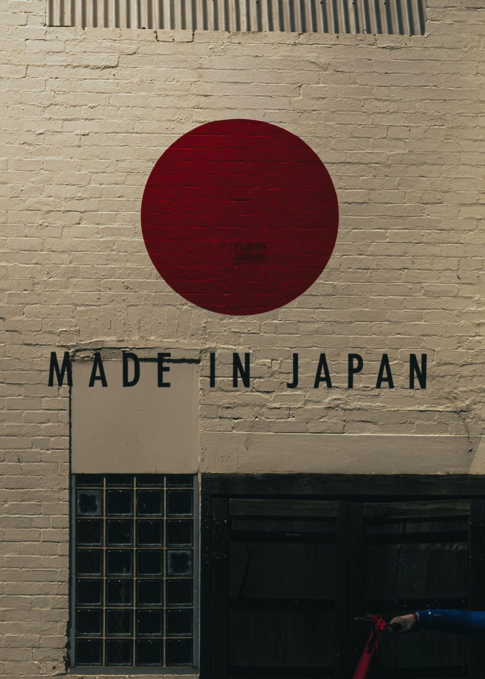 Mural of a red sun on a painted brick wall, reading Made in Japan
